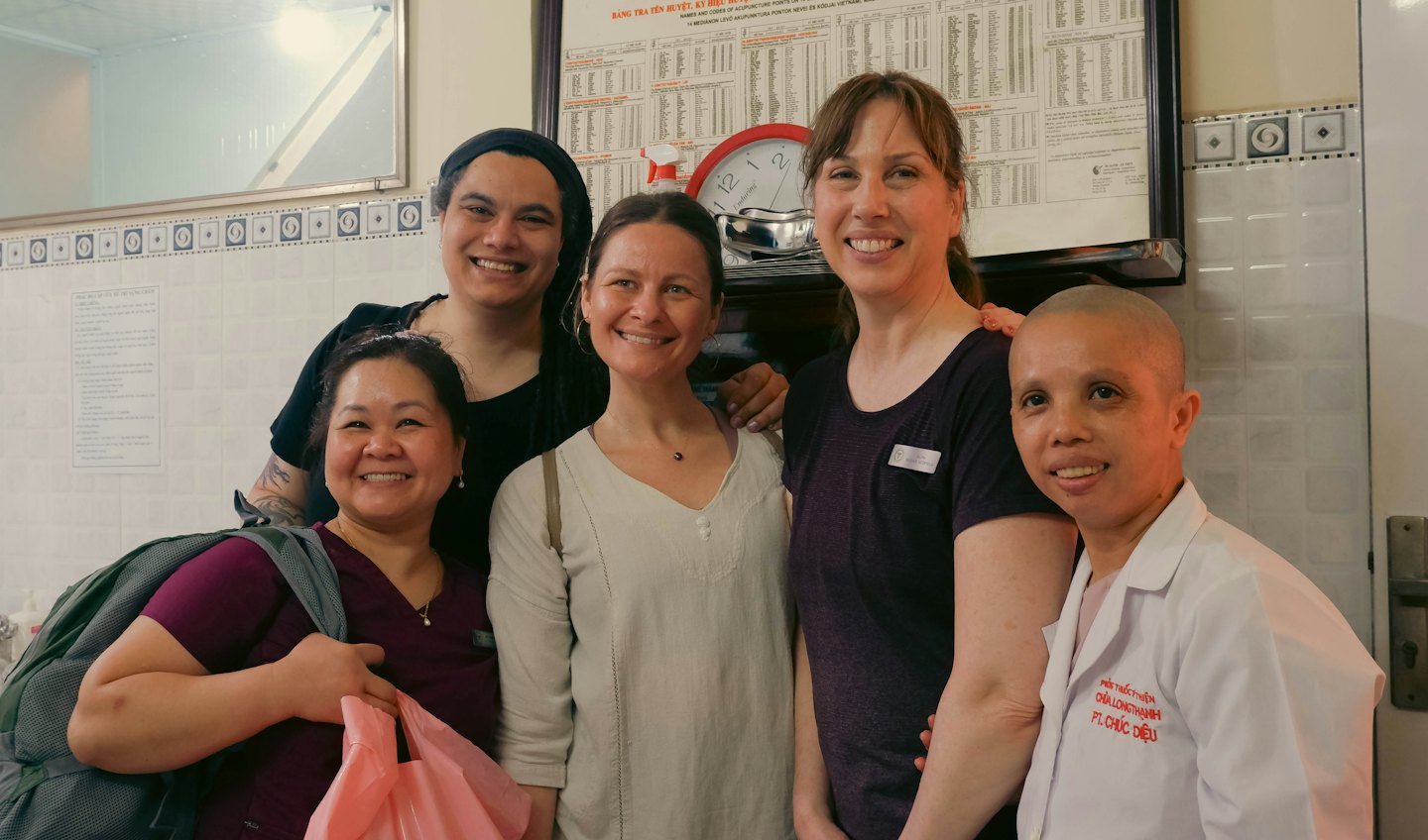 Five smiling people stand together in a community pharmacy.