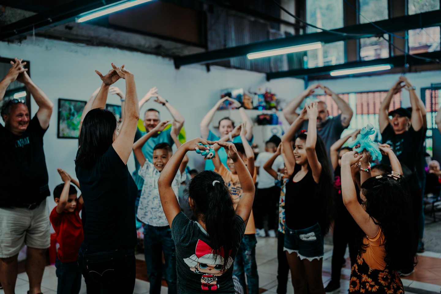 Adults and children raising arms in a bright indoor group activity.